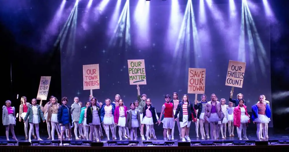 Young performers with protest signs under purple light