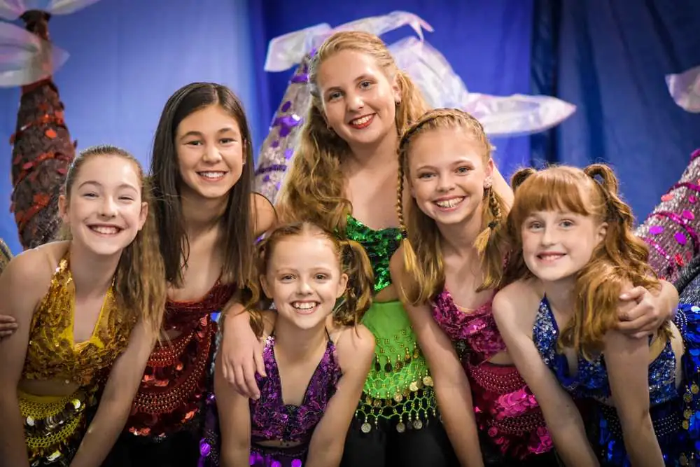 A group of smiling performers in sequins