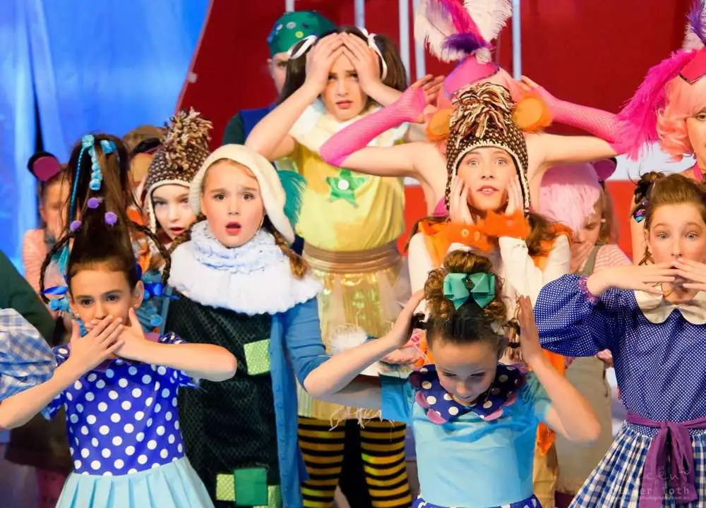 Young performers in colourful costumes, wide-eyed and laughing
