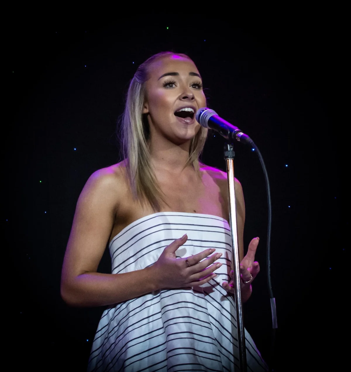 A Pelican performer singing into a microphone on stage